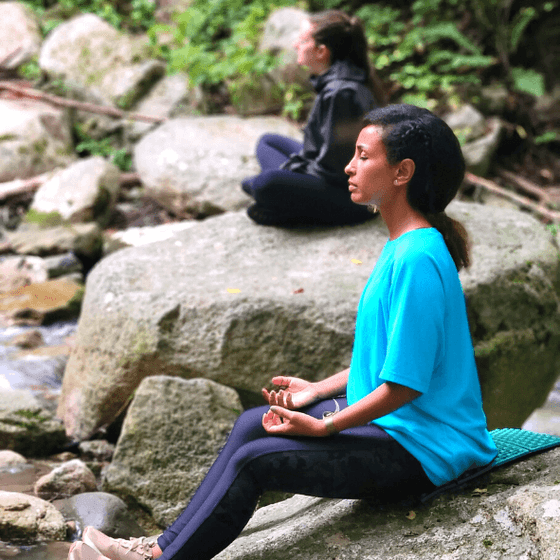 Women meditating by a stream near Honor’s Haven Retreat