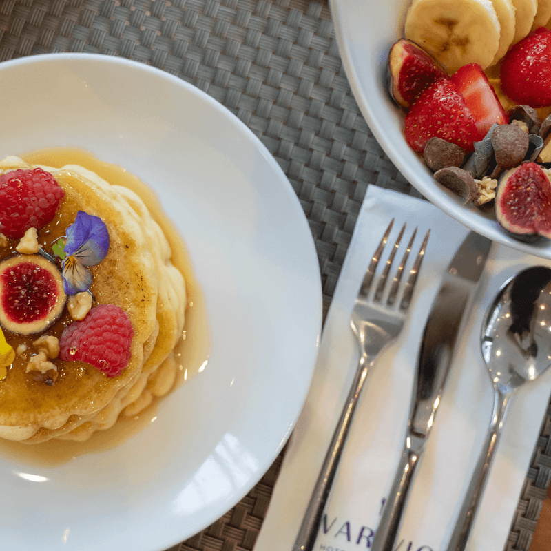 Pancakes with fresh figs and berries beside a fruit bowl breakfast at Warwick Reine Astrid - Lyon