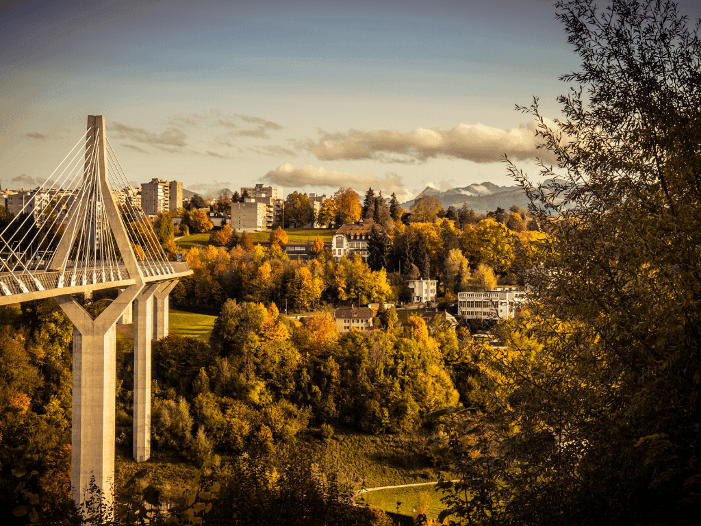 Pont de la Poya bridge spanning a river amid greenery and distant mountains near Hotel des Innovations