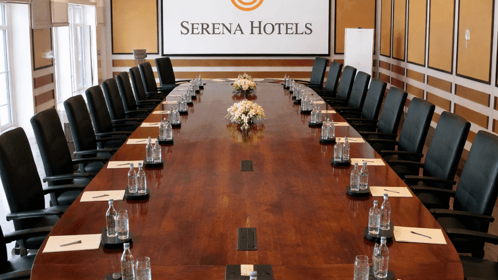 Long mahogany Quetta Meeting Room table with bottled water and Serena Hotels logo for exclusive conferences in Africa