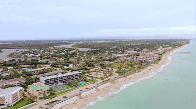 Aerial view of coastline with beach, ocean, homes and waterways under soft cloudy skies near Star Suites Vero Beach