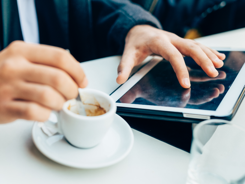 Close-up of a person using an iPad while preparing coffee on a table at The Earl