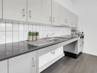 Modern kitchen with white cabinetry, gray countertops, stainless steel sink, and white tile backsplash at Springfield Central.