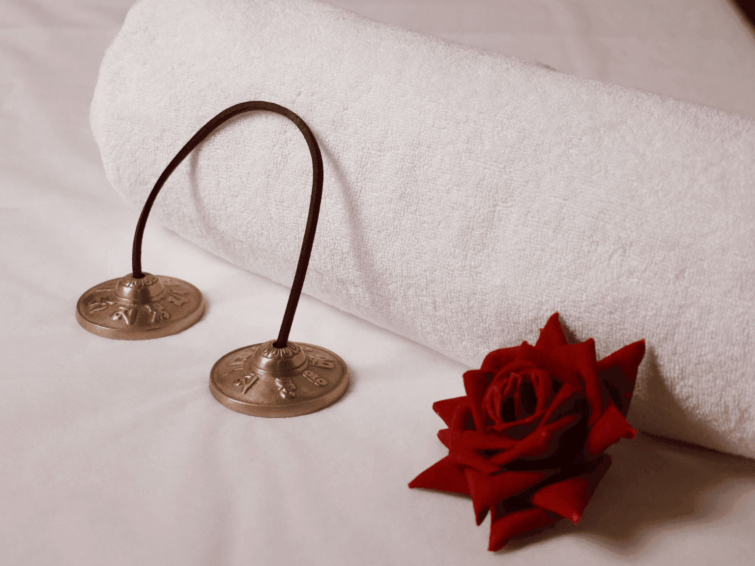 Rolled towel with bronze cymbals and a red rose, creating a serene spa mood in Dreamworks Spa at DAMAC Maison Distinction