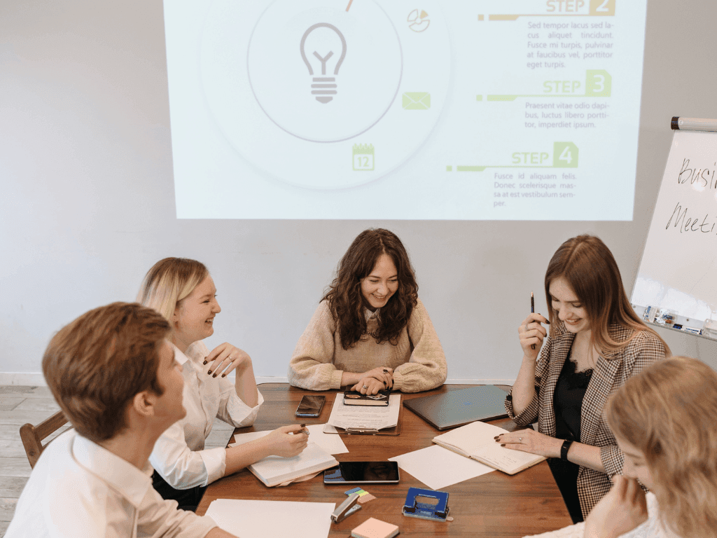 Professionals collaborating around a table as a lightbulb-themed presentation displays at Hotel des Innovations
