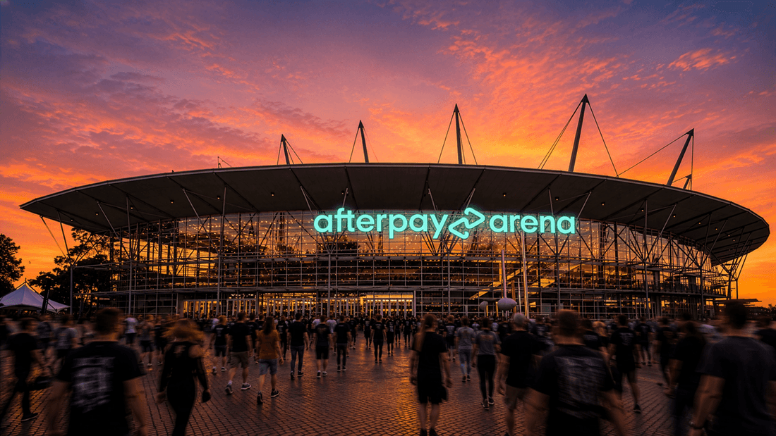 Modern arena with illuminated Afterpay Arena signage at sunset with crowds gathering outside the venue entrance.