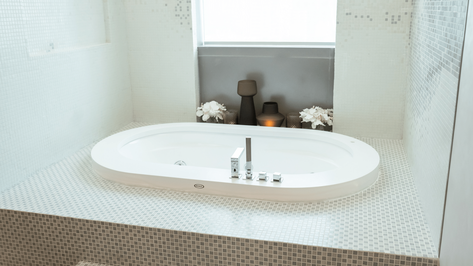 Modern spa bathroom featuring a sleek white jacuzzi tub set against a mosaic tiled platform at Paramount Hotel Midtown