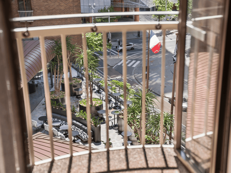 Hotel balcony wooden deck with safety railing overlooking lush tropical garden courtyard below