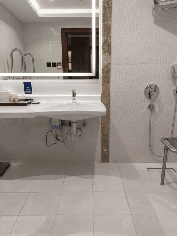 Accessible room bathroom with roll-in shower, grab bars and foldable shower chair