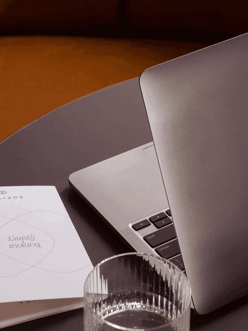 Hotel room with king bed, yellow armchair, wooden desk and large curtained window