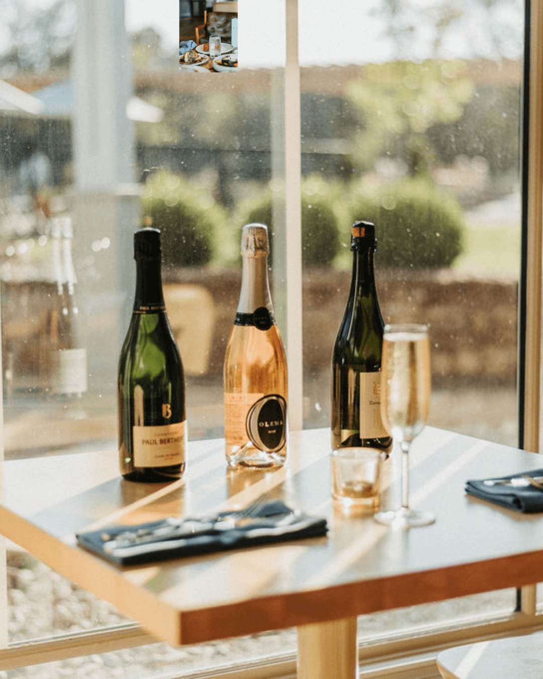 Two bottles of wine placed on the dining table bathed in sunlight.