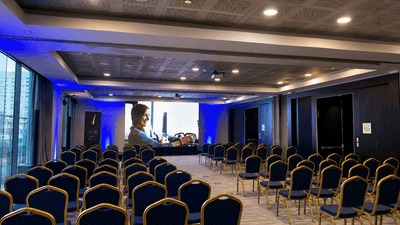 Rows of classroom-style tables and chairs facing projector screens displaying presentations in Libertad at Veranda Hotel