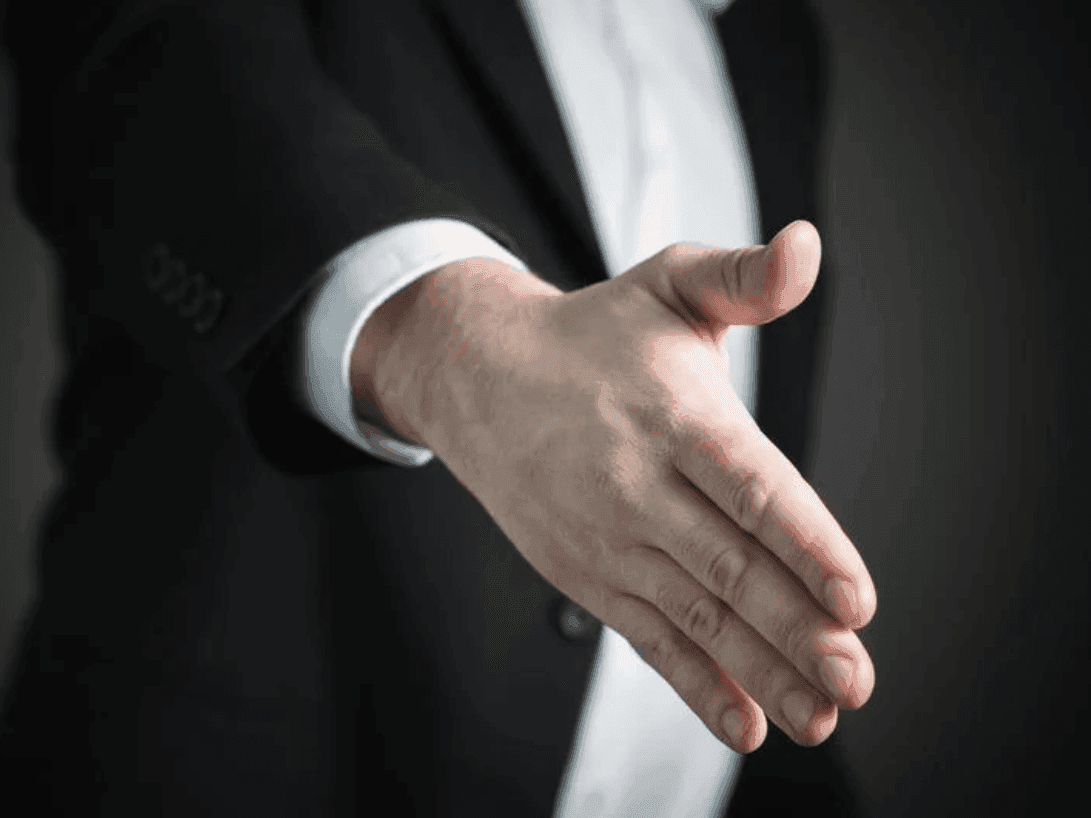 Close-up of a man giving hand for a handshake at Nesuto Hotels