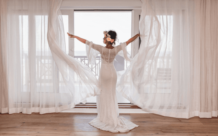 Bride opening the curtains by the balcony at our wedding venue in Avalon