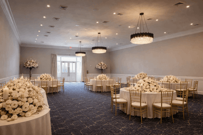 The Crystal Ballroom set for an event with round tables, white floral displays, and chandeliers at The Markham Hotel