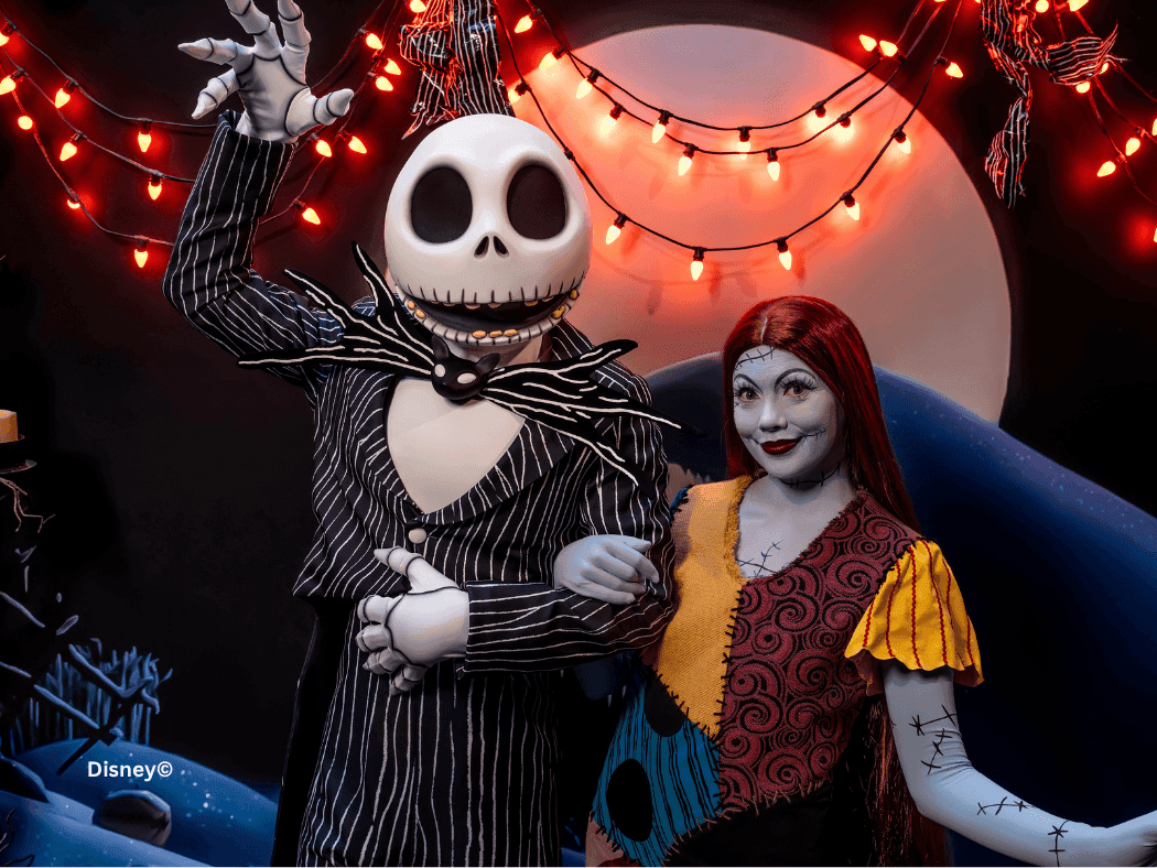 Jack Skellington and Sally characters pose together under festive string lights with a glowing moon backdrop.