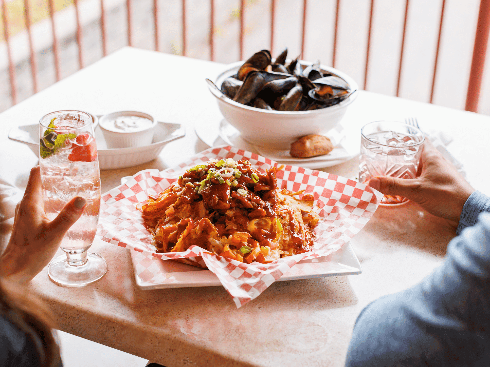 Spread of food including loaded nachos, mussels, and drinks on a table at Club 19 inside Rodd Brudenell River Resort