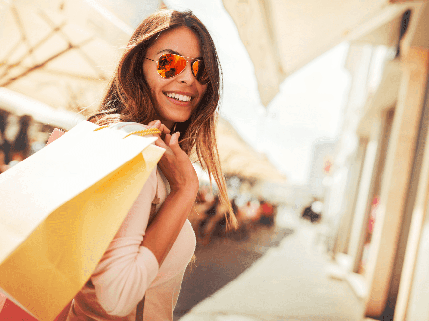 A woman smiling with hanging a shopping bag at Amora Hotel