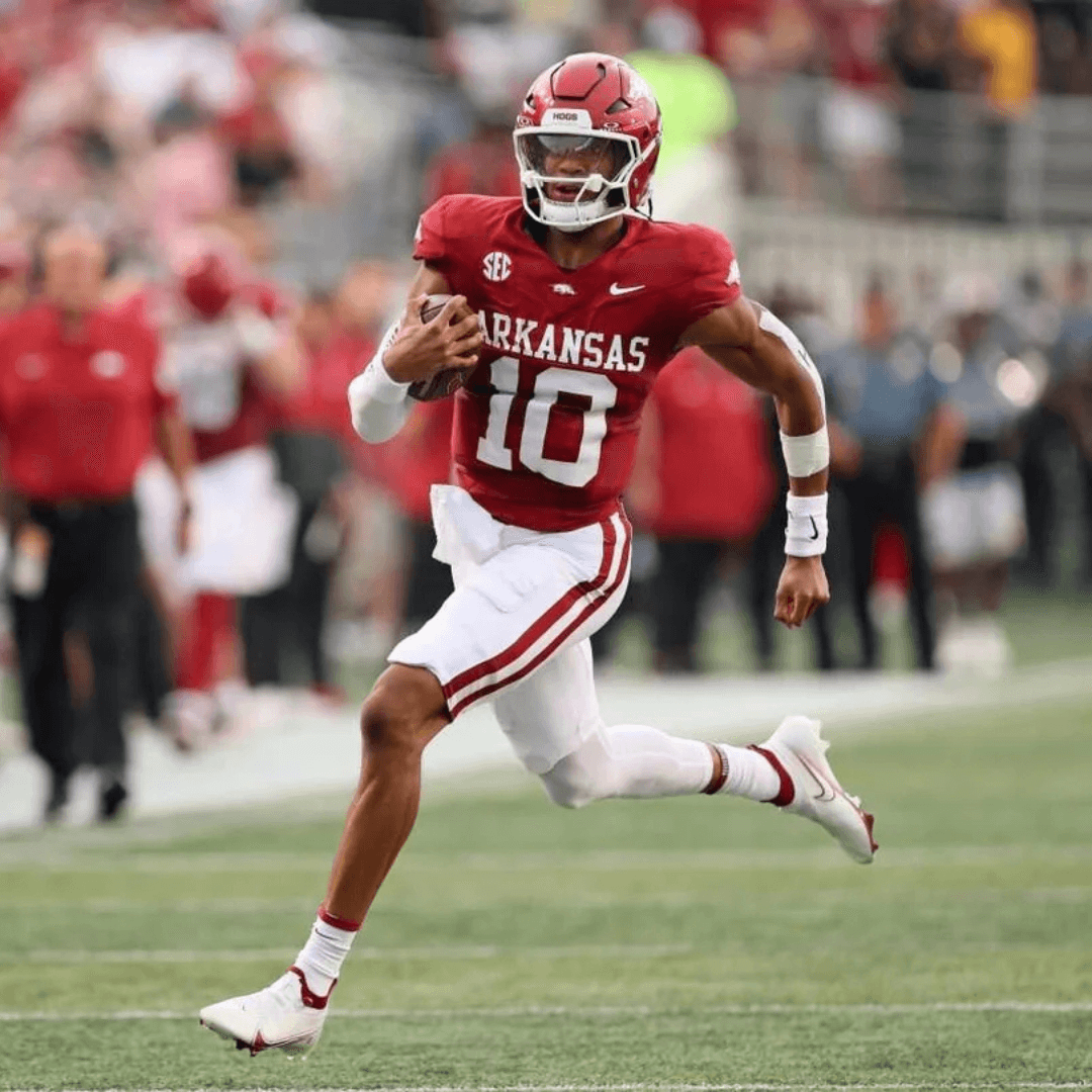 A football star on Arkansas football team spriting down the feild with ball in arm.