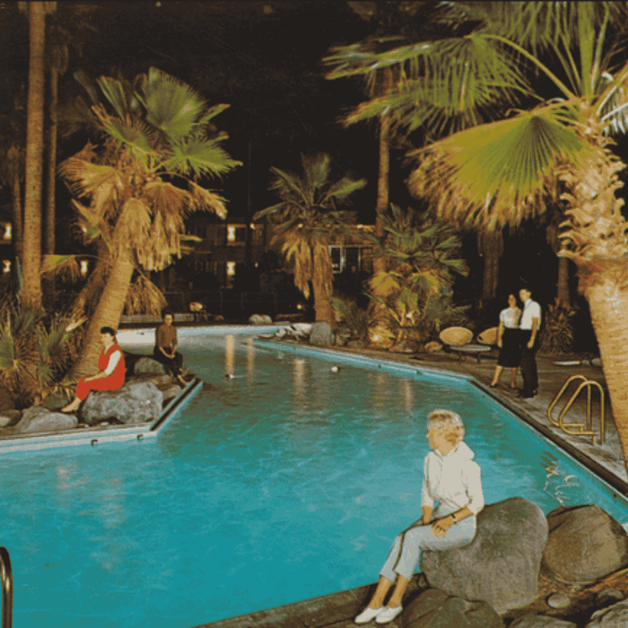 People sitting poolside with palm trees at Grand Legacy at The Park Anaheim