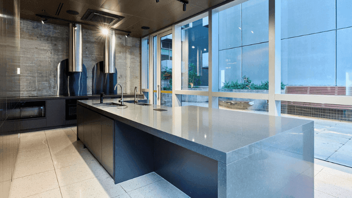 Modern kitchen with large central island, glass windows, and adjacent seating area outside.