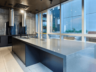 Modern kitchen with large central island, glass windows, and adjacent seating area outside.