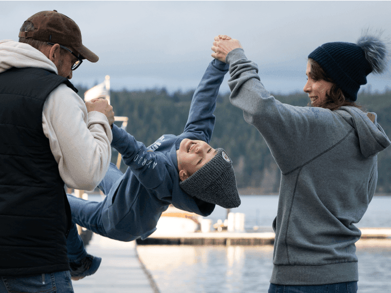 kid swinging in parents arms