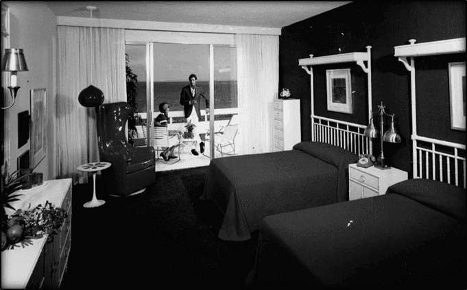 Vintage photo of a room with two beds and a couple on a balcony overlooking the ocean in July 1962 at EL Conquistador Resort