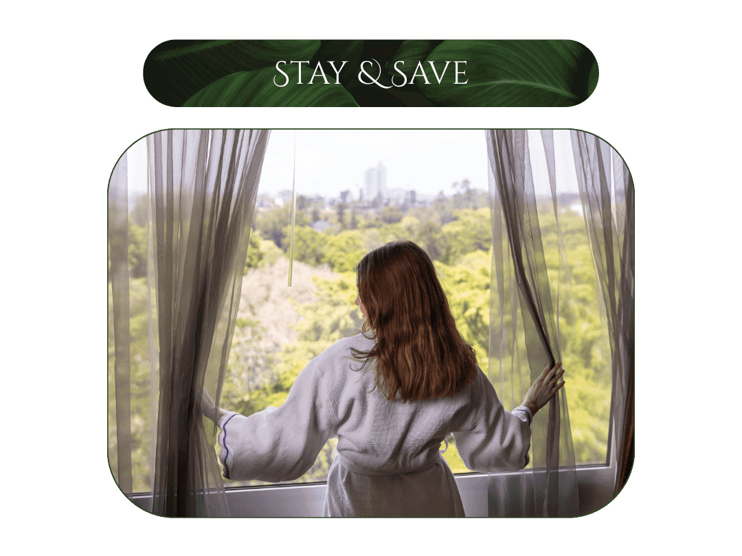 Woman in bathrobe opening curtains and looking out the window with the Botanic Gardens view.