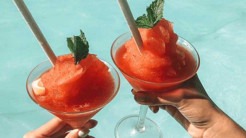 Two frosty, red slushie cocktails are held, featuring Classic & Specialty Cocktails at Mercure Hotel Townsville