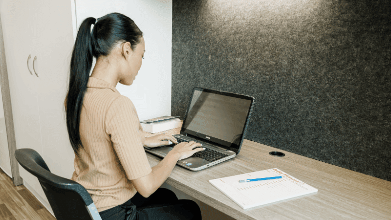 Woman working on laptop with documents at desk in StudentLiving Darwin.