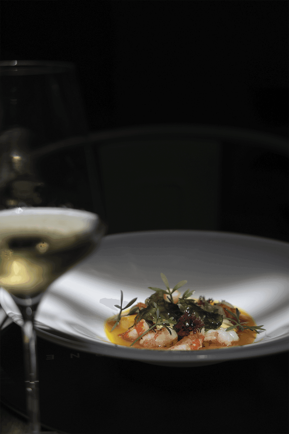 Glass of champagne next to a beautiful dish of shrimp and herbs at the restaurant in The Rhyland Hotel in Flushing, NY