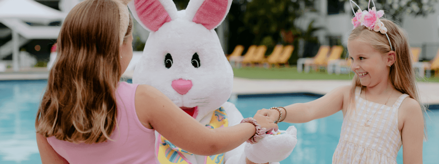 Two young girls playing with an Easter bunny by a pool for Stay, Play, Save These Easter Holidays.