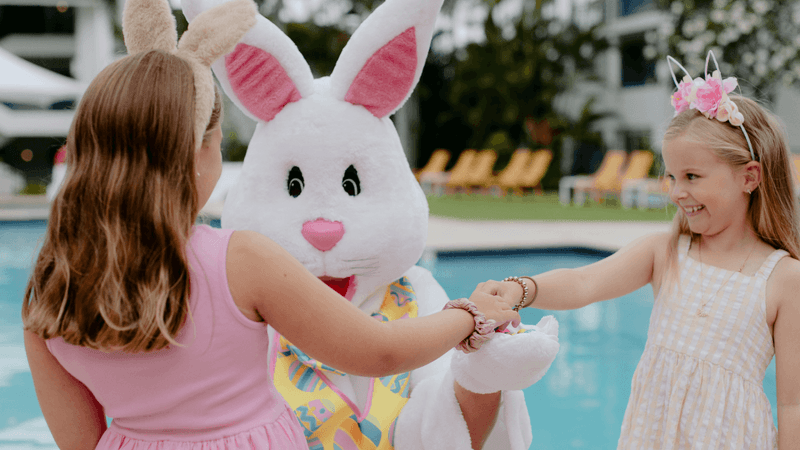 Two young girls playing with an Easter bunny by a pool for Stay, Play, Save These Easter Holidays.