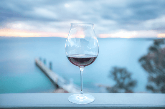 Close-up of a wine glass on a balcony railing with a Lake backdrop at Freycinet Lodge