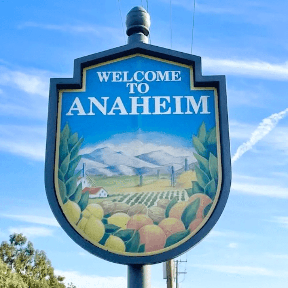 Welcome to Anaheim sign with oranges and scenic view under a blue sky.