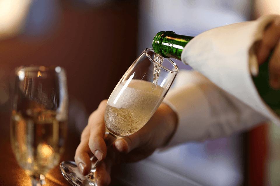 Bartender pouring sparkling champagne into a glass at the bar area of The Met Hotel Leeds, England