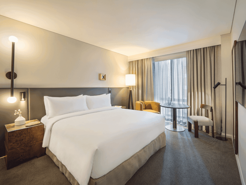 Hotel suite with king bed, seating area, large windows and contemporary furnishings