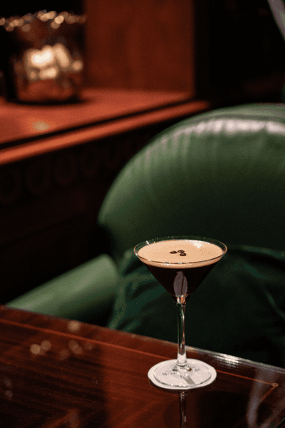 Cocktail espresso martini sur table basse devant banquette en velours vert à l'Hotel Westminster Warwick Paris
