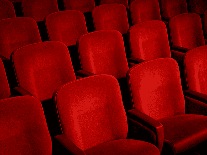 Empty red velvet seats at theatre.