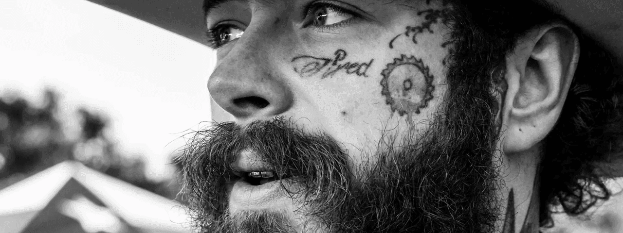 A bearded man with tattoos on his face and neck promoting the BIG ASS World Tour 2026.