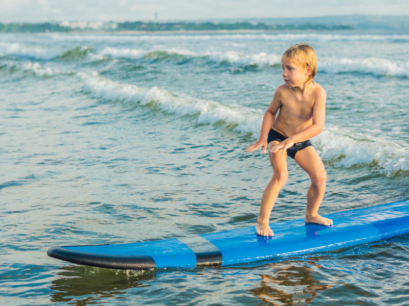 Child on a surf board rides a wave near our Wildwood Crest NJ hotel