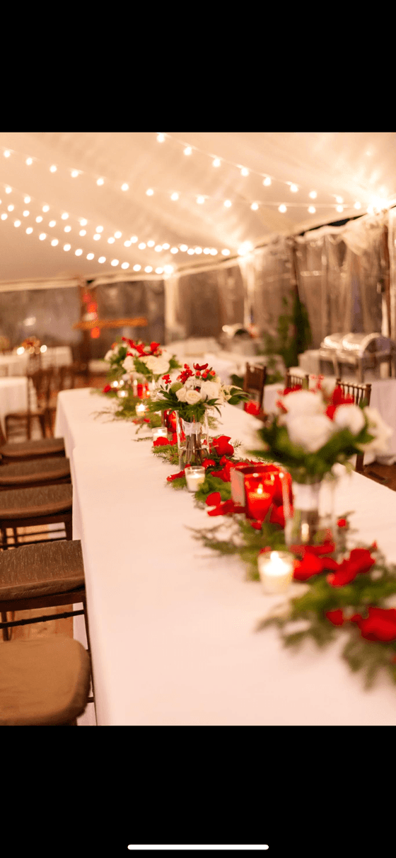A long table decorated with red and white flowers, candles, and greenery at The Clifton Hotel in Charlottesville, Virginia.