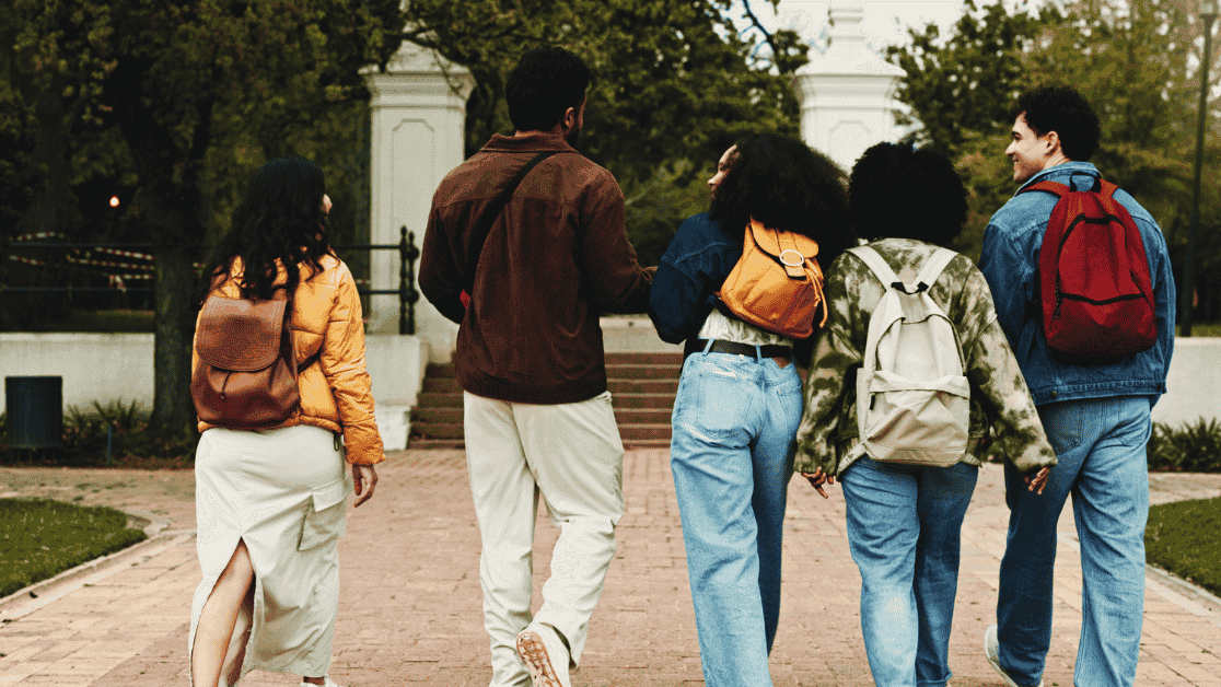 Group of students with backpacks walking together on a path.
