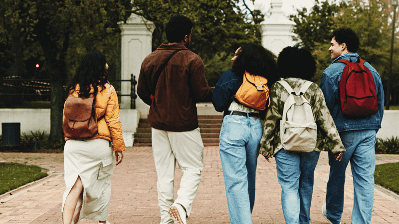 Group of students with backpacks walking together on a path.