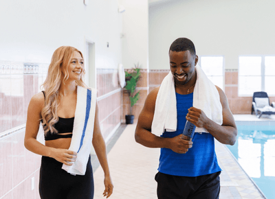 Couple walking with towels by the indoor swimming pool and nearby lounge chairs at Rodd Crowbush Golf & Beach Resort