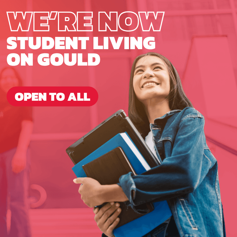 Smiling student holding books with text we're now student living on Gould open to all.