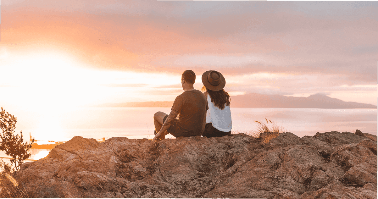 Two people sitting on Castle Hill’s summit watching the sunrise.
