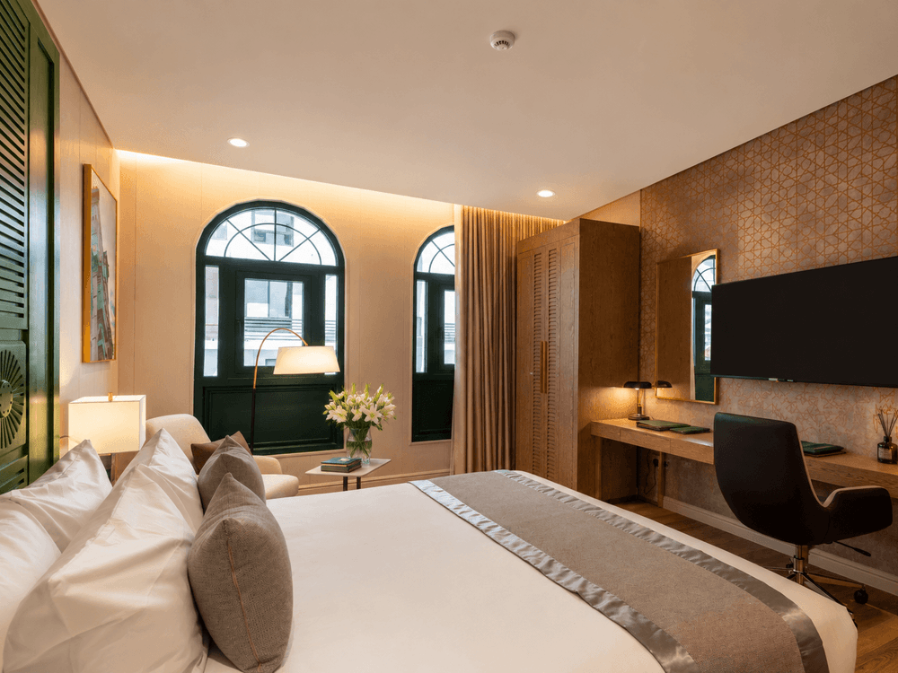King bed facing wall-mounted TV above sleek wooden work desk with chair in Accessible room at Naviti by Warwick Jeddah
