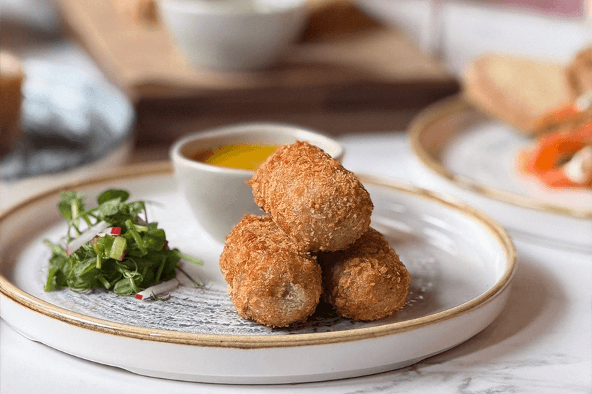 Croquettes stacked on a plate with a side of mixed greens and radish in Gott\'s Bar & Kitchen at The Met Hotel Leeds, England